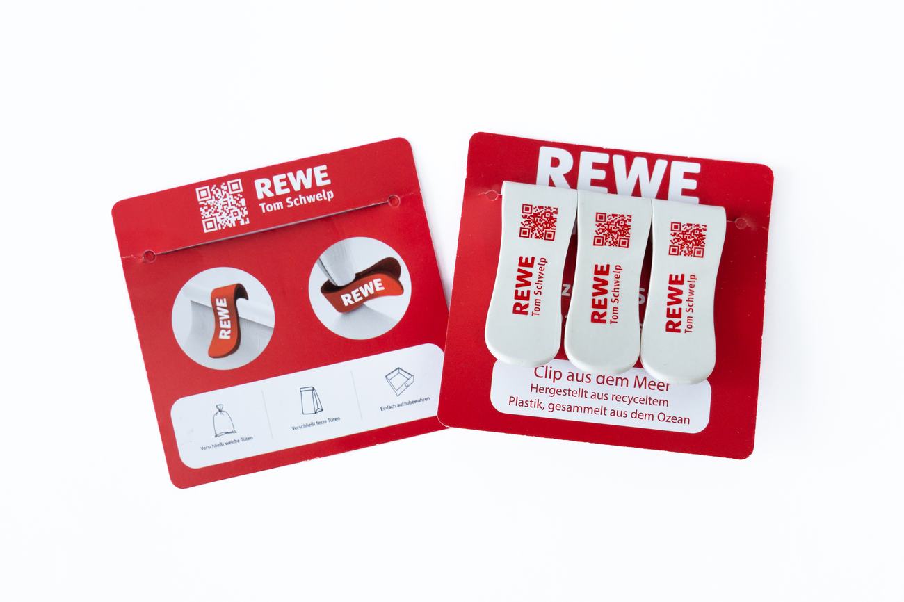 Vorder- und Rückseite einer bedruckten Trägerkarte mit drei REWE Ocean Clamps